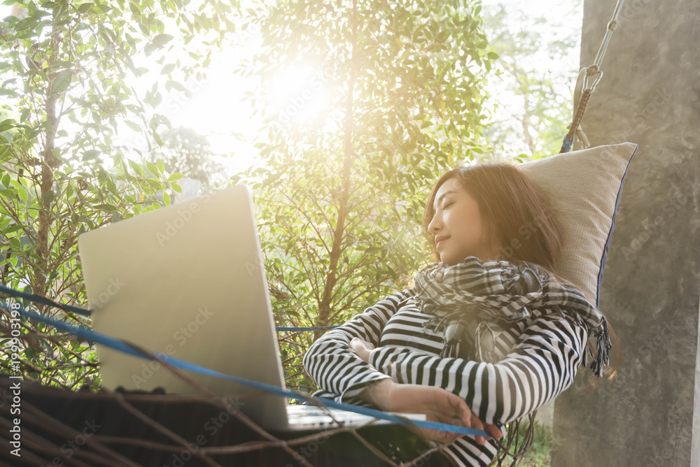 Young woman sleeping in hammock while use laptop, freelance life style conceptual, work anywhere