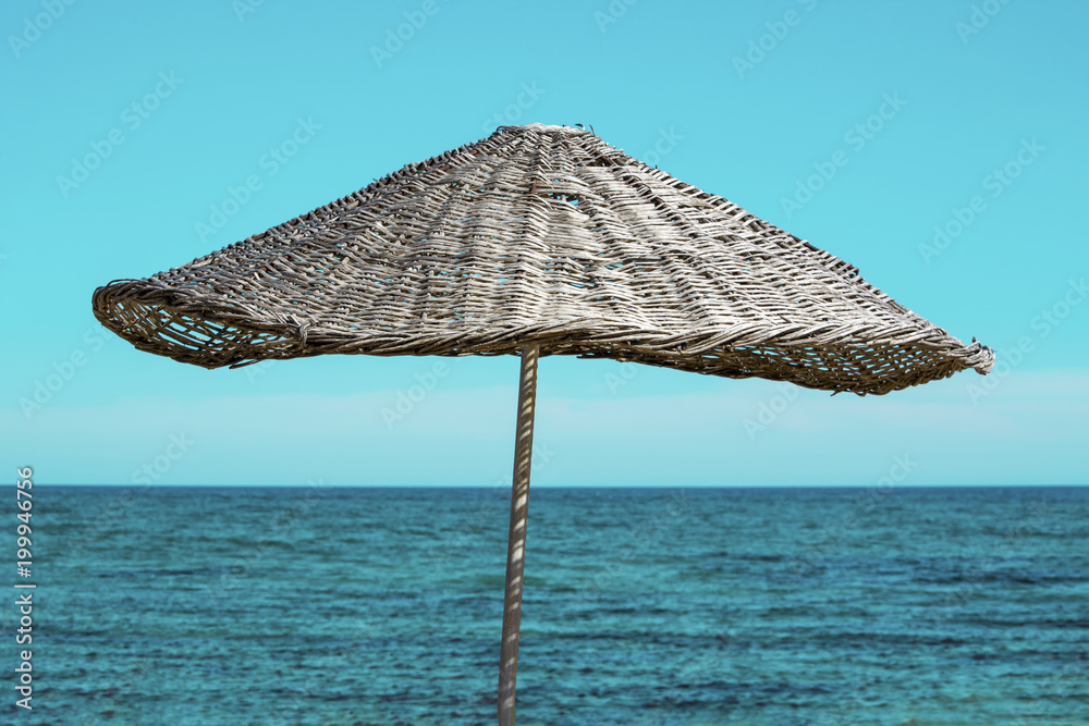 Braided straw umbrella on the coast