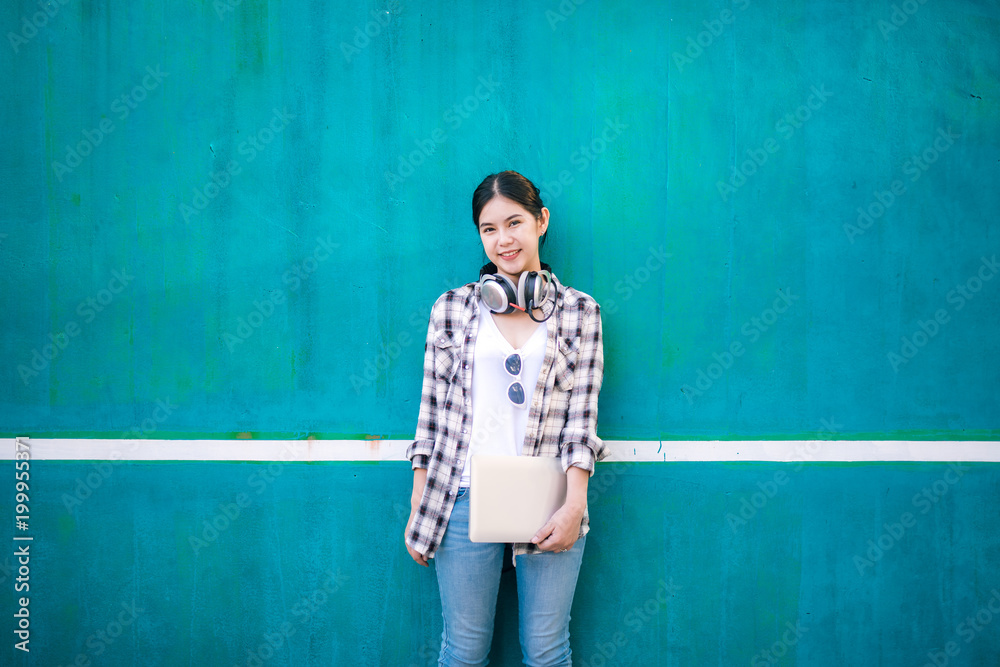 戴着笔记本电脑耳机快乐微笑的亚洲女学生画像