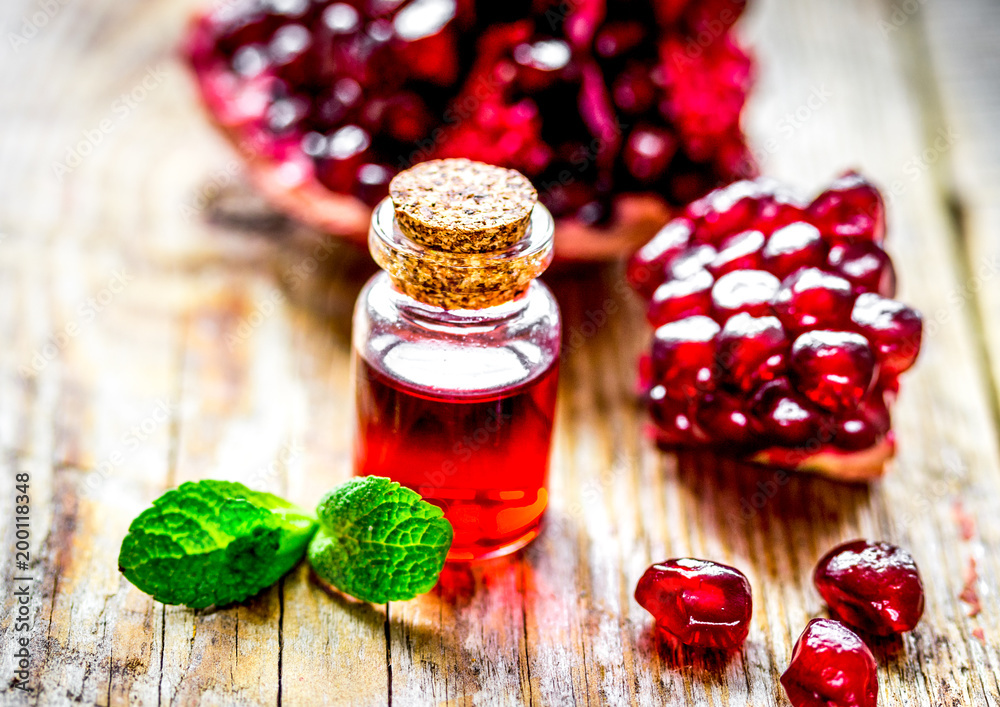 sliced pomegranate and extract in glass on wooden background