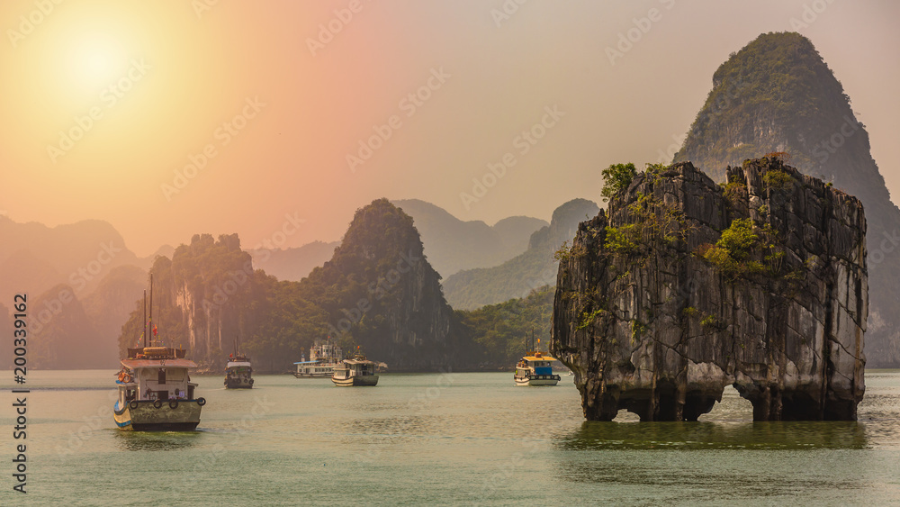 美丽的日落旅游船锚漂浮在南下龙湾的石灰岩悬崖岩石中