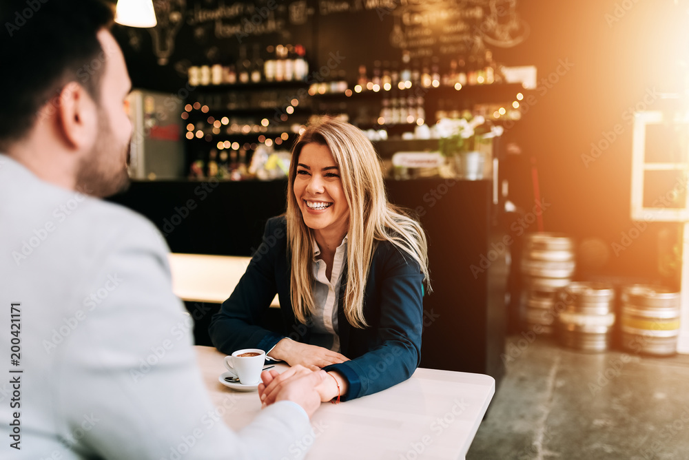 Smiling couple holding hands at the cafe.