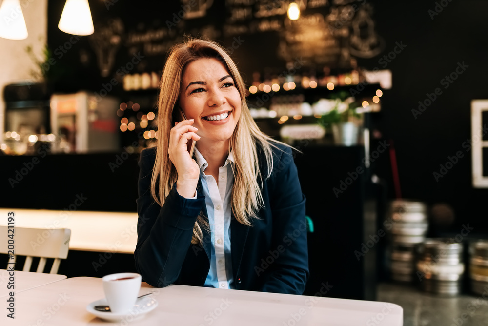 Portrait of a smiling business woman talking on a phone at the restaurant.