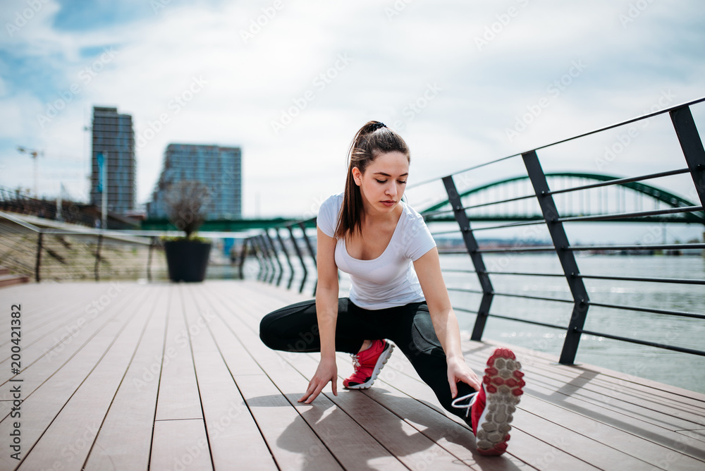 Girl training on the quay stretching legs and doing exercises.