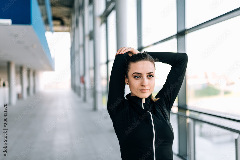 Close up image of fit girl stretching her arms indoors.