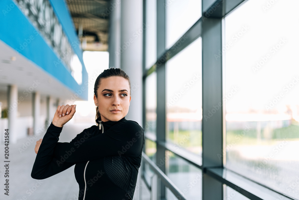 Close up image of fit girl stretching indoors.