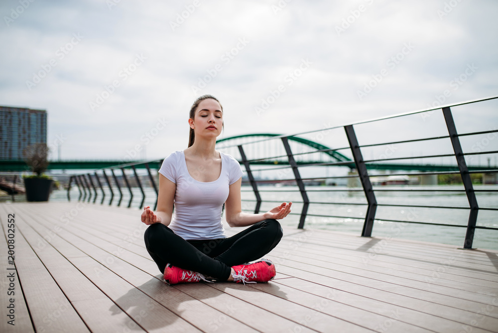 年轻漂亮的健身运动女性在河边做户外慢跑。