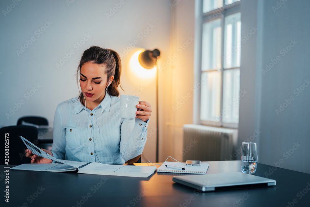 年轻的女人在看书，手里拿着一杯茶或咖啡。