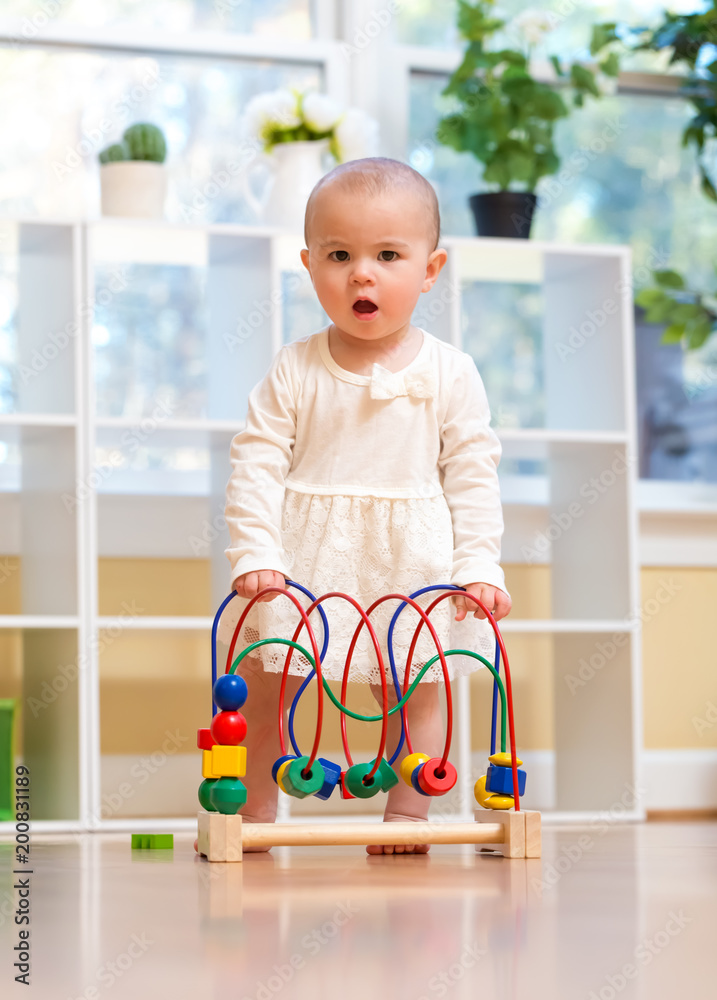 Happy toddler girl playing with toys in her house