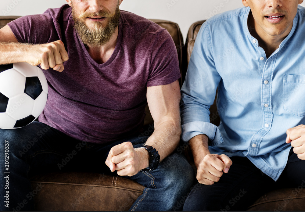 Man sitting together on a couch watching sport