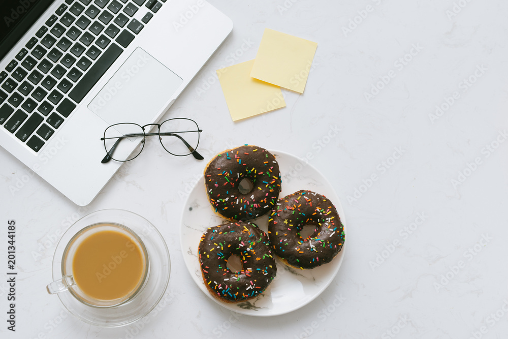 Food in the office. Donuts on working desk.