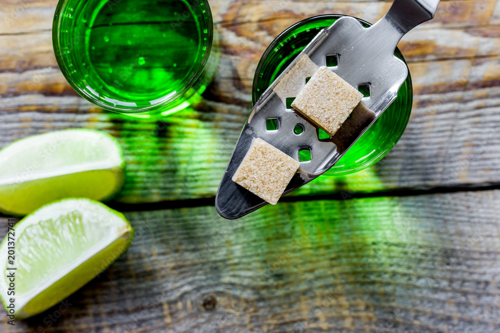 absinthe with sugar cubes in spoon on wooden background top view