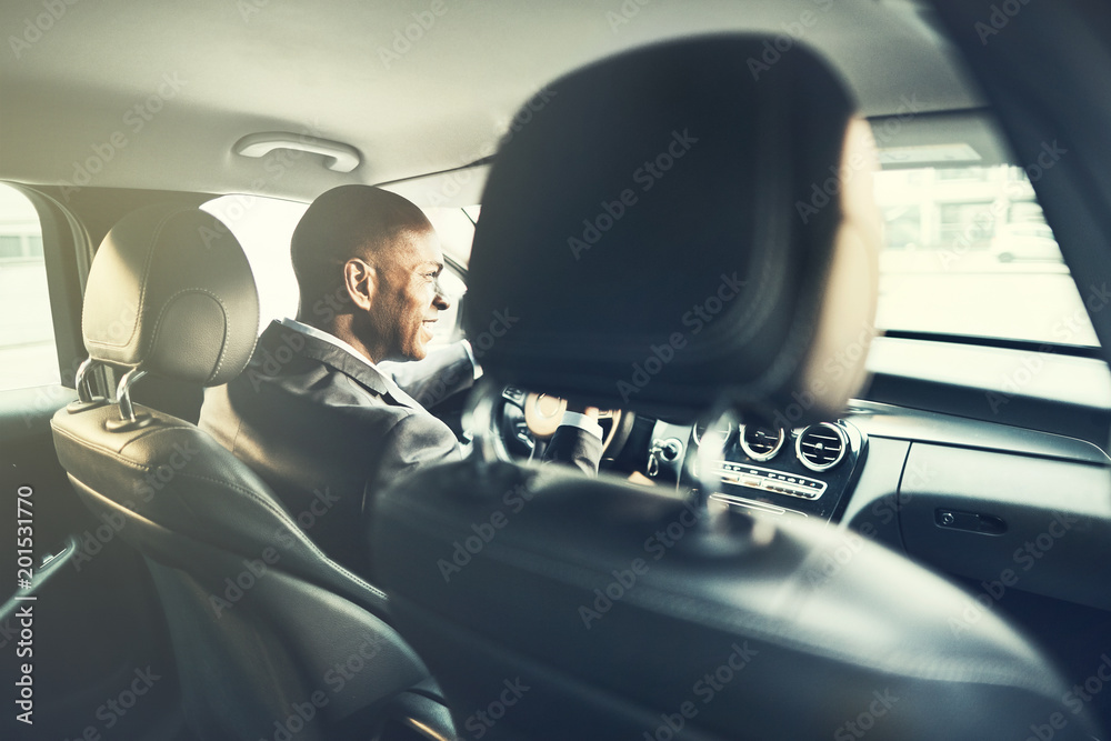 Smiling African businessman driving a car through the city