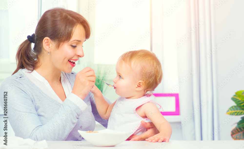 母亲用勺子喂养女婴。婴儿食品。健康家庭