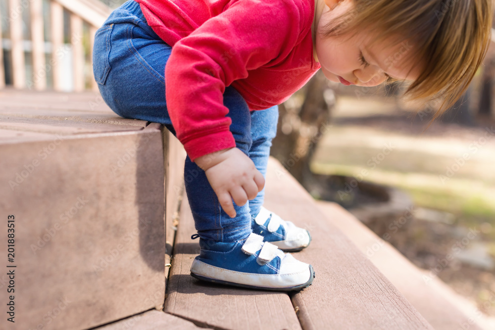 Happy toddler boy tying his sneakers outside