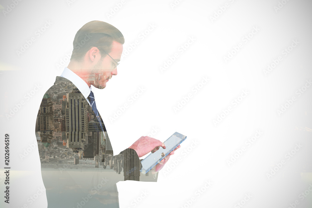 Businessman in reading glasses using his tablet pc  against room with large window looking on city