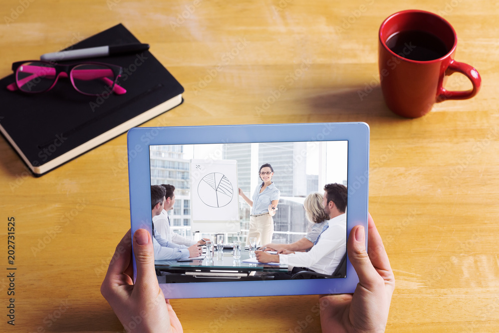 Businesswoman using tablet at desk against business people in office at presentation