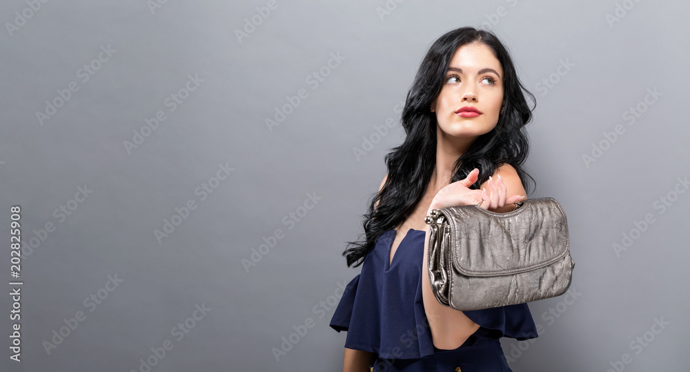 Fashionable woman with luxury handbag on a silver background