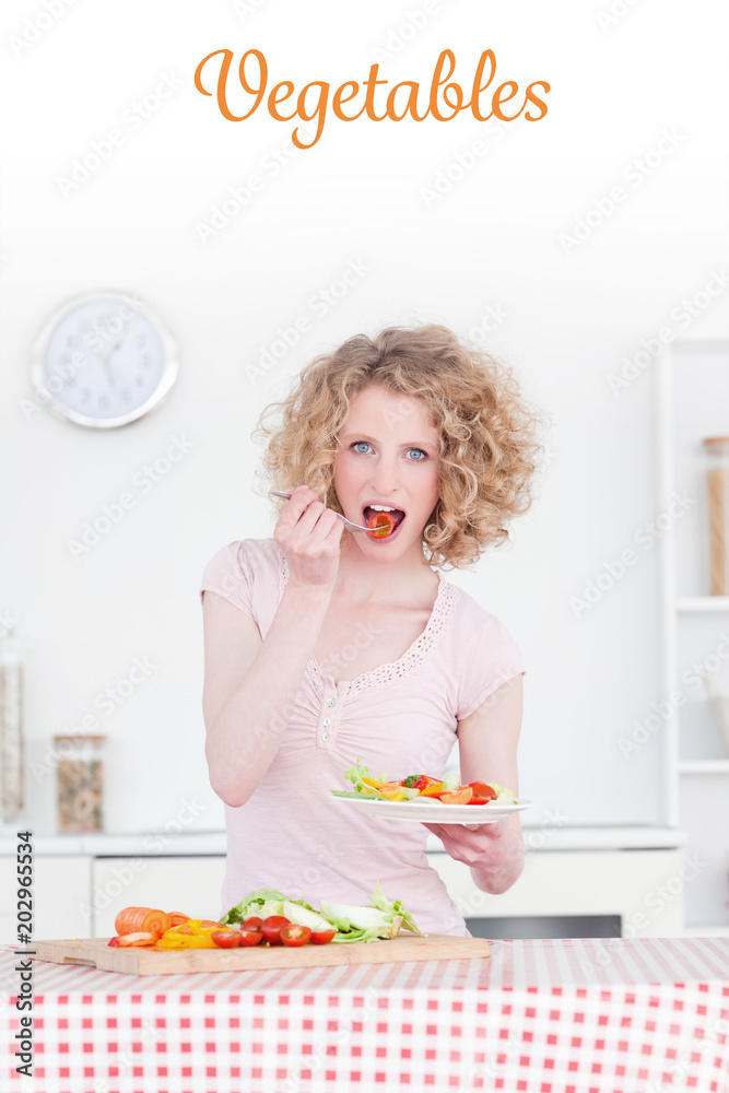 The word vegetables against beautiful blonde woman eating some vegetables in the kitchen