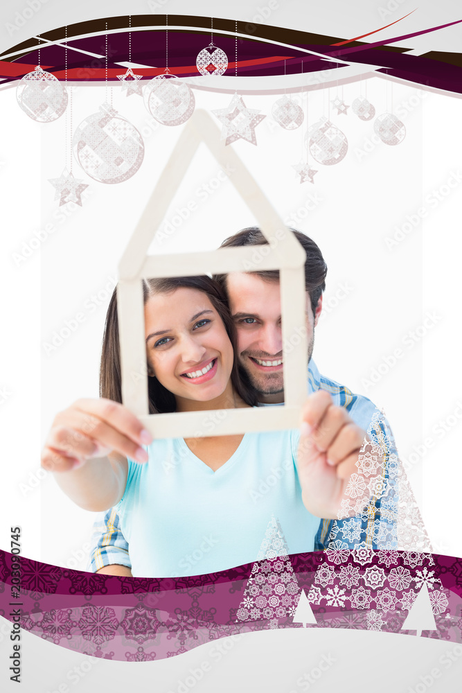 Happy young couple with house shape against christmas frame