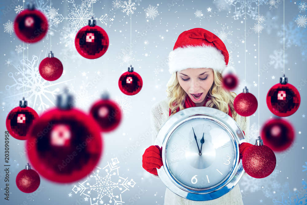 Happy festive blonde with clock against snowflake pattern