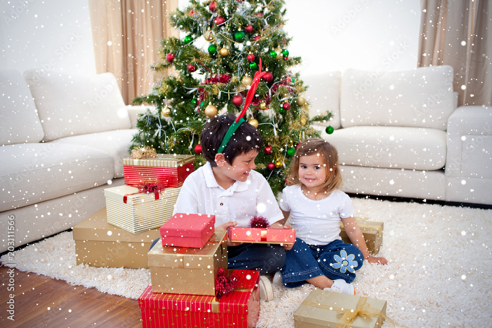 Happy children celebrating Christmas at home against snow falling