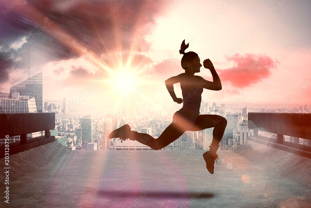 Fit brunette running and jumping against sun shining over road and city