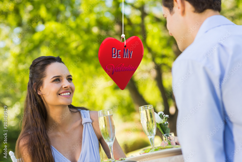 Couple with champagne flutes sitting at an outdoor caf√© against be my valentine