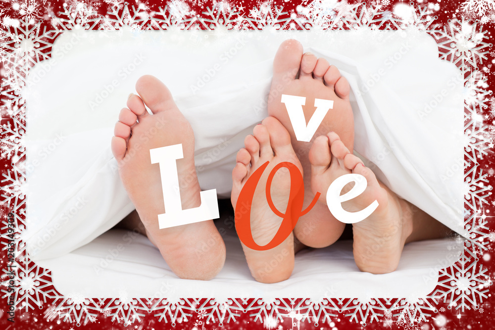 Composite image of pair of feet under duvet with love text against snow