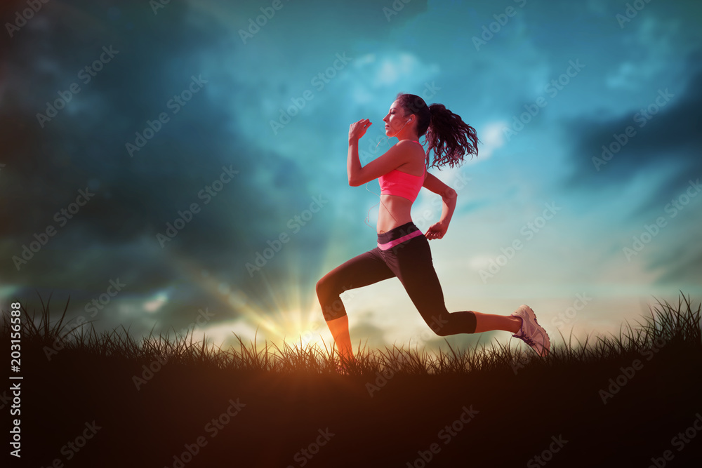 Full length of healthy woman jogging  against blue sky over grass