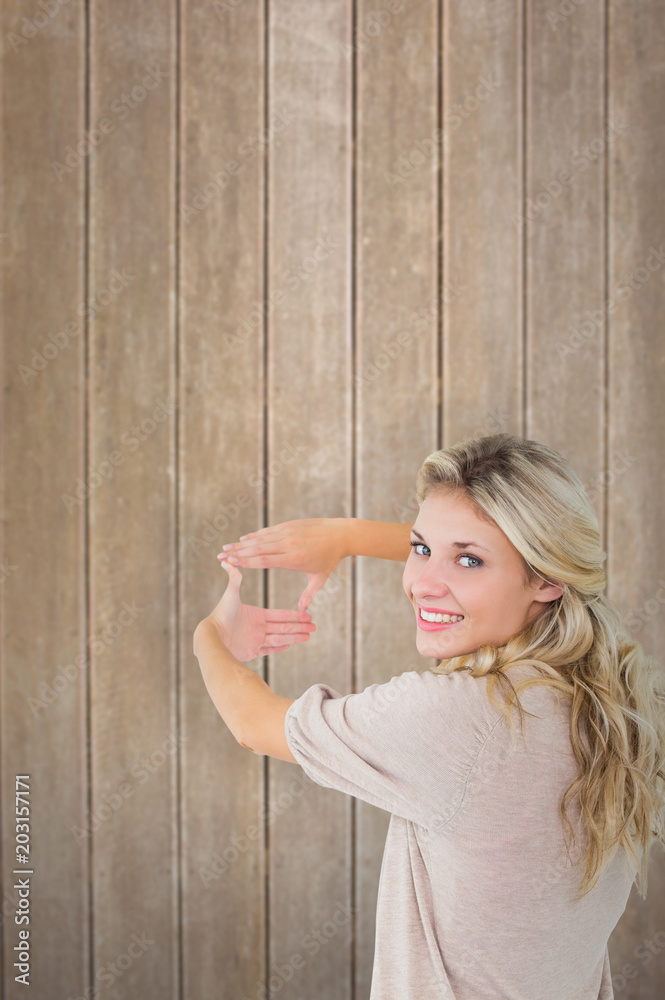 Attractive young blonde framing with her hands against wooden surface with planks