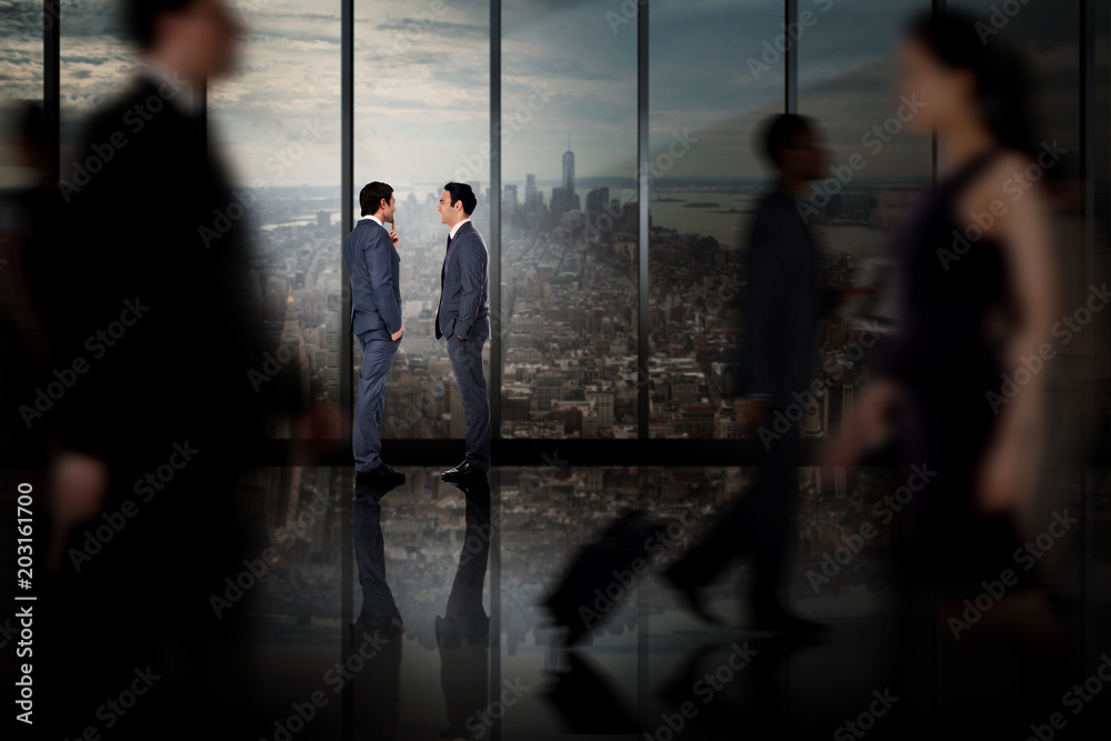 Businessmen talking against room with large window looking on city