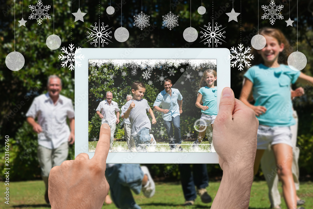 Hand holding tablet pc against happy multi generation family racing towards camera