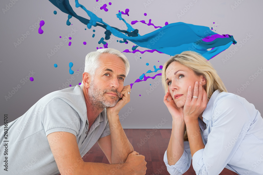 Thoughtful couple lying and looking up against room with wooden floor