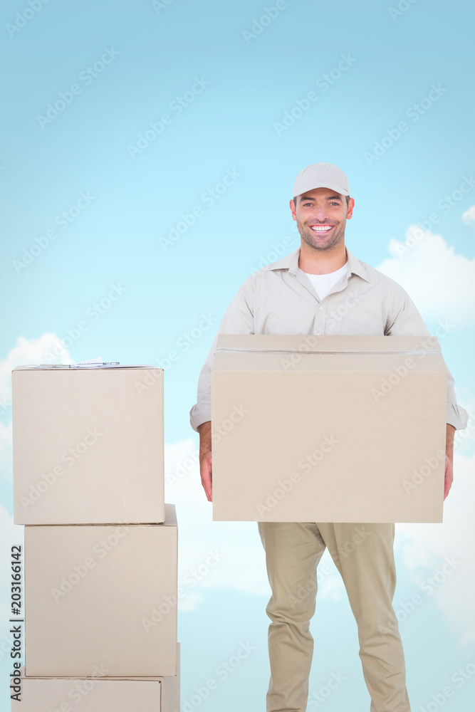 Courier man carrying cardboard box against blue sky