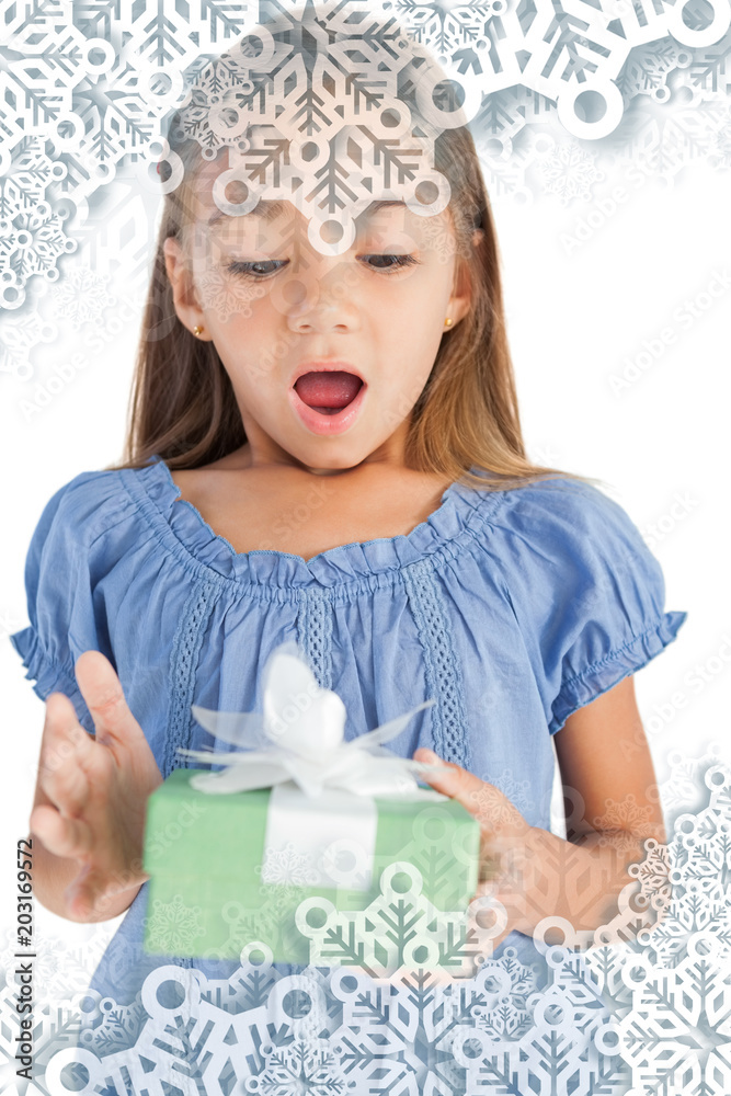 Composite image of Surprised little girl holding a wrapped gift with snowflakes on silver