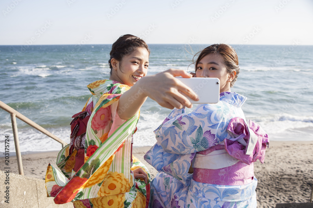 浴衣女性たちは海辺で写真を撮っている