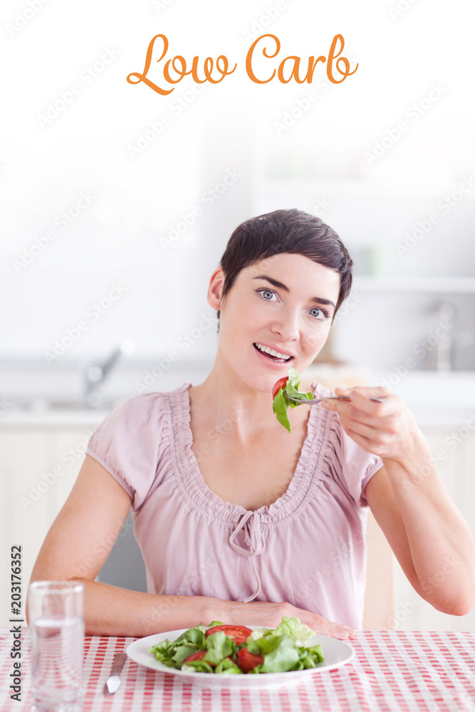 The word low carb against cheerful brunette woman eating salad