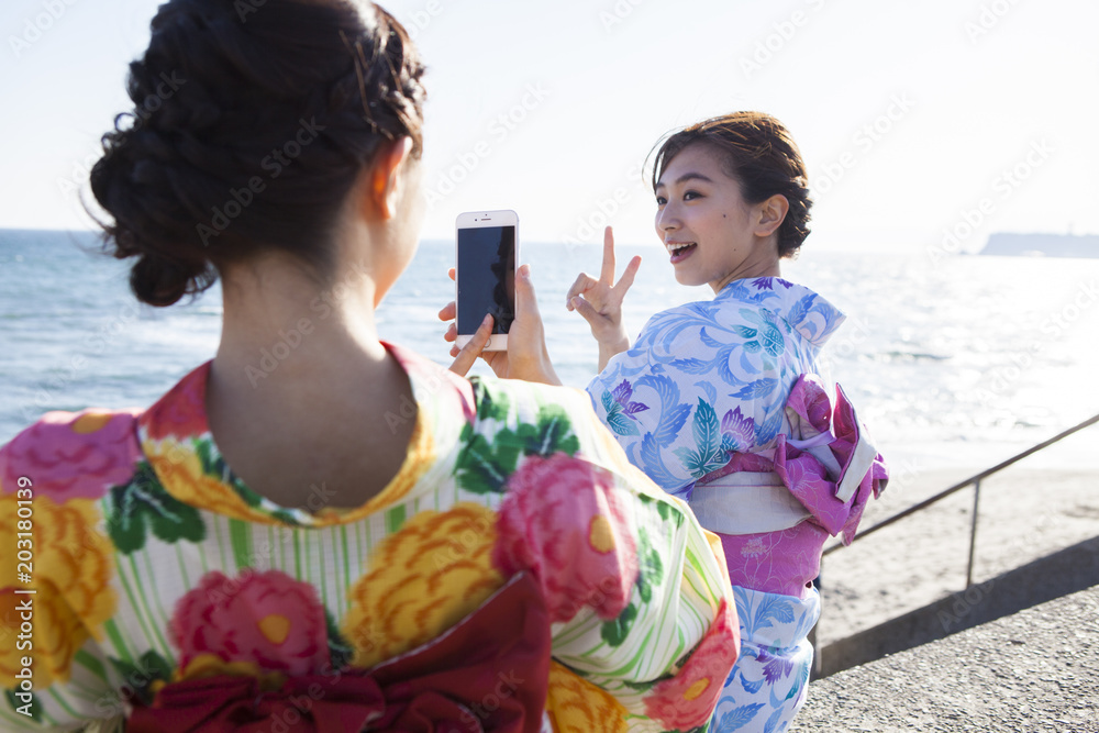 浴衣女性たちは海辺で写真を撮っている