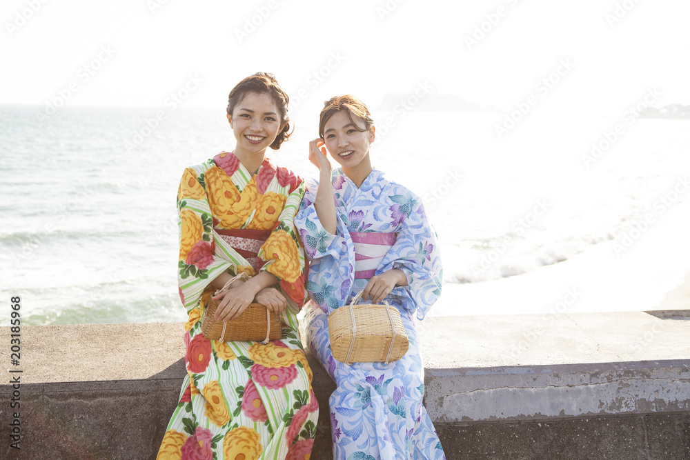 堤防に座っている美しい浴衣女性