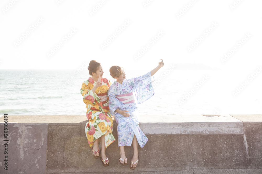 海辺でセルフショットを撮影している浴衣女性たち