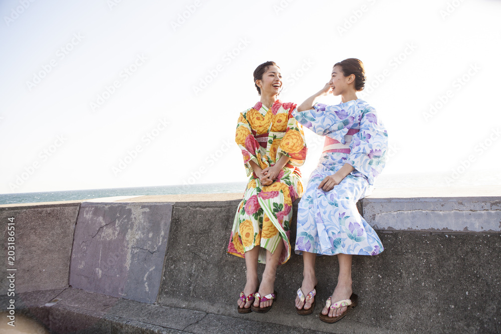 堤防に座って花火大会を待っている女性たち