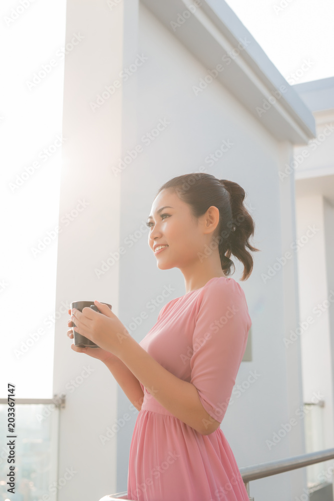 年轻女子拿着咖啡杯微笑着看着镜头