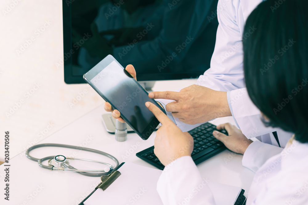 Two doctors analysing and consulting over medical record in modern hospital. Asian doctors talking a