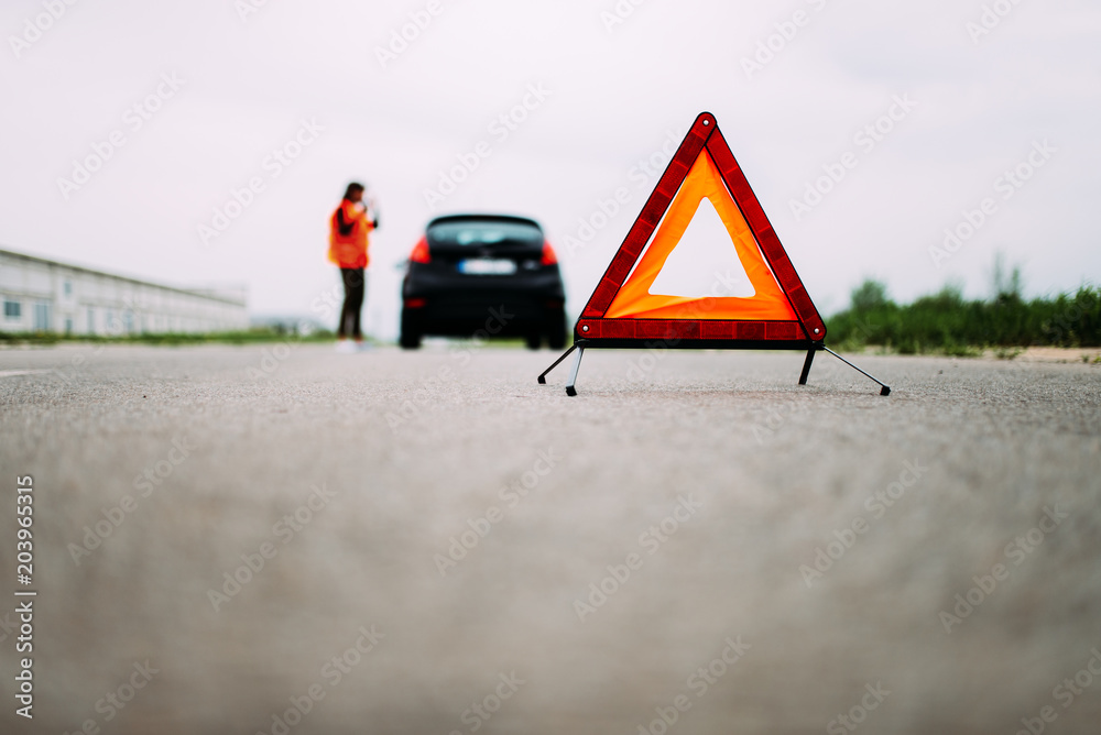 红色预警在道路的前景中发出天籁声。背景中是穿着反光背心的女孩。