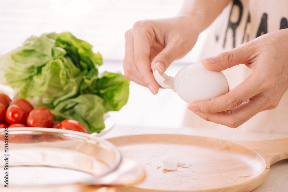 女性手正在剥鸡蛋。该女性在家准备早餐。煮鸡蛋在