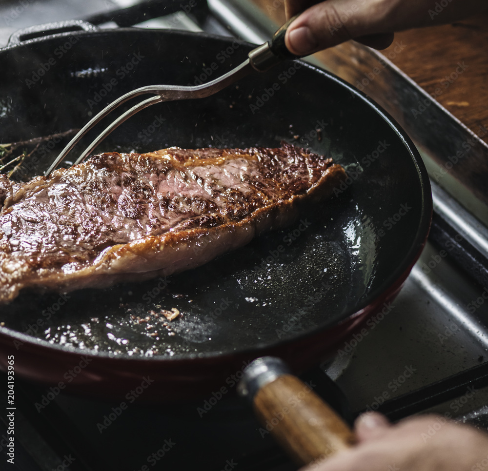 A chef cooking steak in a pan food photography recipe idea