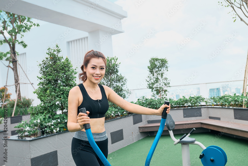 亚洲女性在户外健身房操场设备锻炼