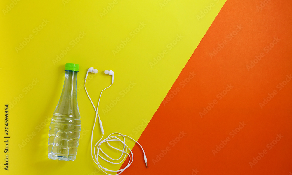 close up of water bottle and earphones on retro color paper background,fitness background concept.