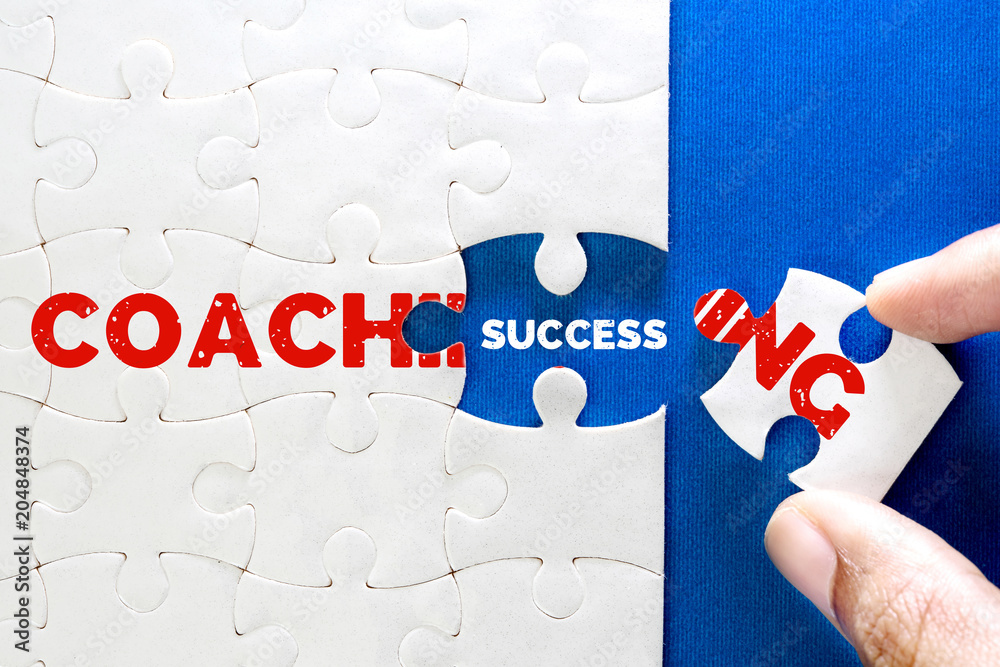 一块白色拼图的特写，带有COACHING和SUCCESS文本，商业辅导的概念